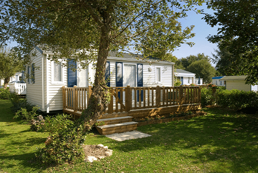 A mobile home with wooden steps and a tree.