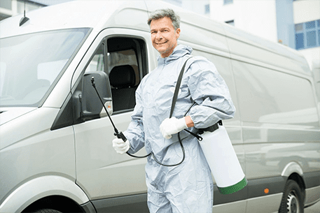 A man in a white suit holding a spray bottle.