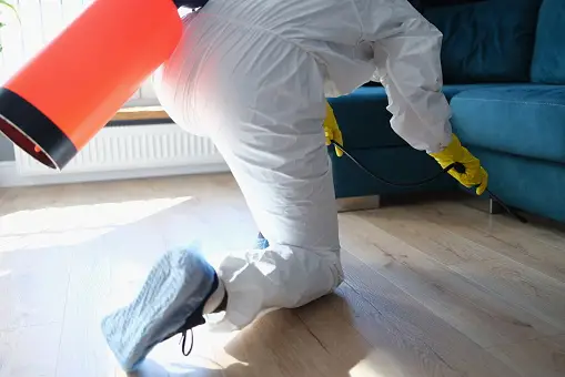 A person in white suit and yellow gloves cleaning the floor.