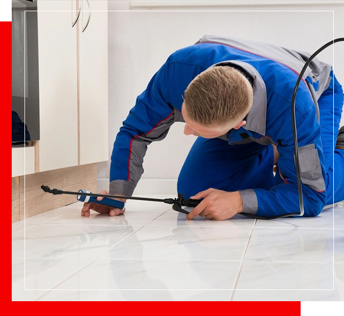 A man in blue work clothes kneeling on the floor.