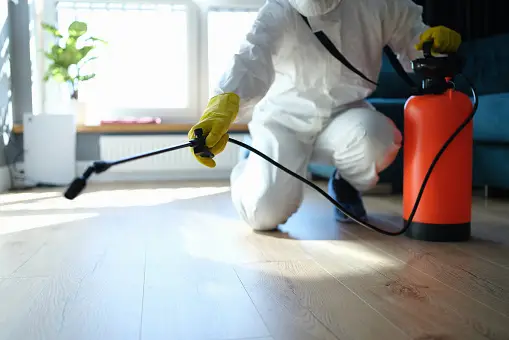 A person in white suit spraying water on the floor.